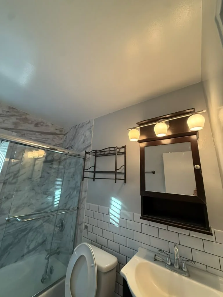 Bathroom vanity with marble wall, wide mirror and sconce lighting