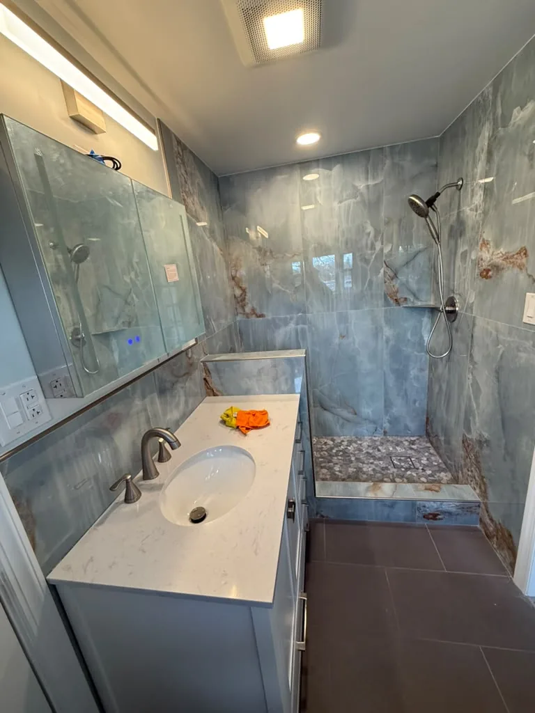 Finished bathroom with full-slab marble shower surround and floating vanity