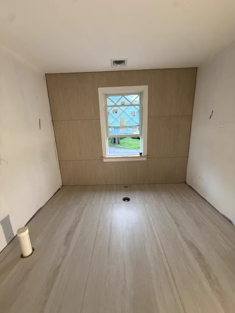 Bathroom with wood panel wall, window and plank flooring