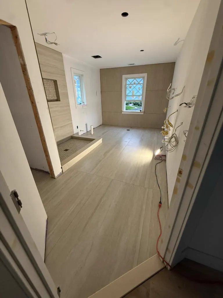 Primary bathroom with travertine shower, window and wood feature wall