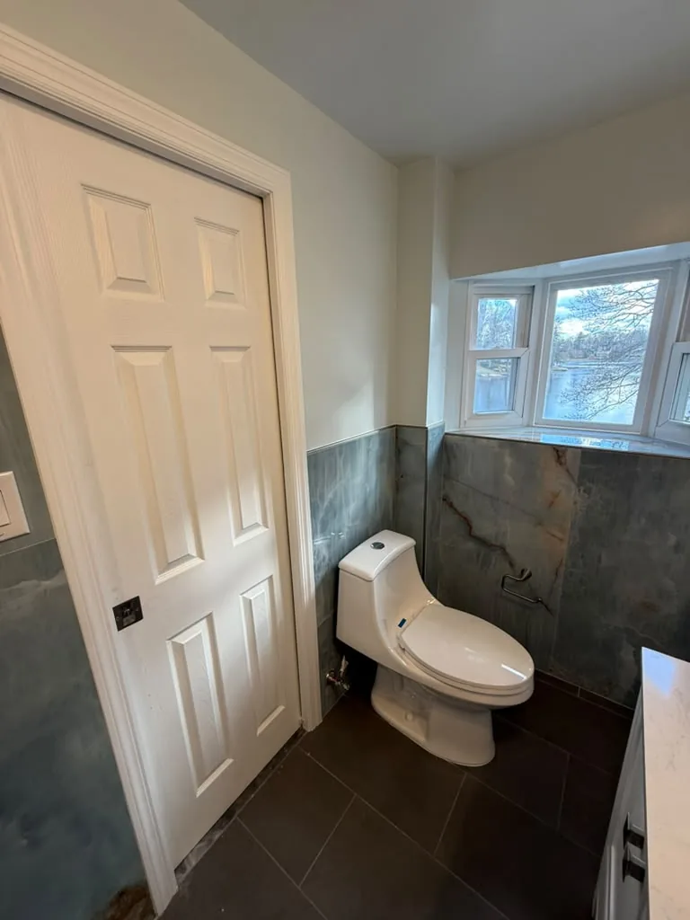 Bathroom with stone wall tile, dark floor and white trim