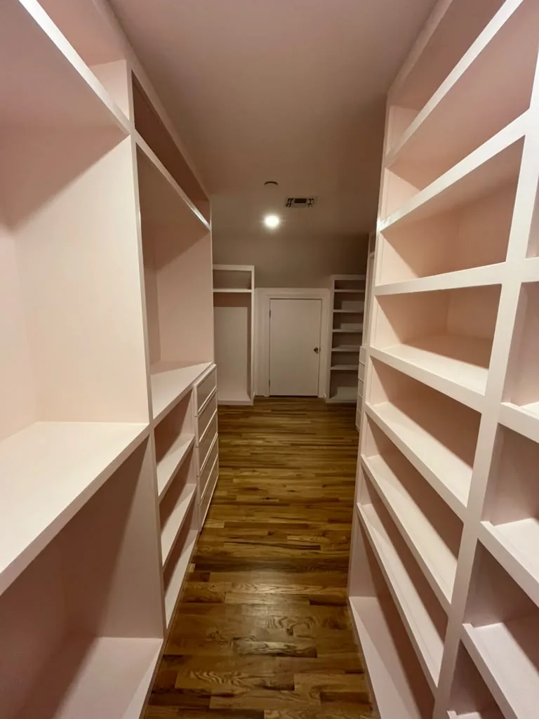 Custom white walk-in closet shelving over hardwood floors