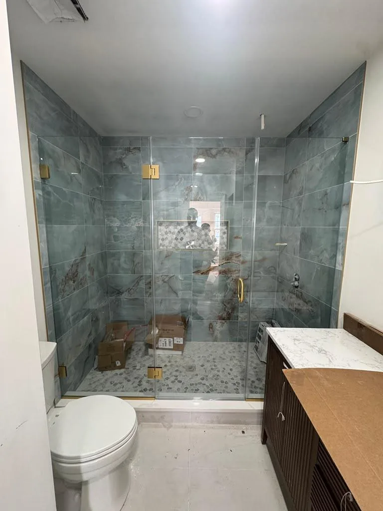 Frameless glass enclosure with gold hardware over a blue stone shower