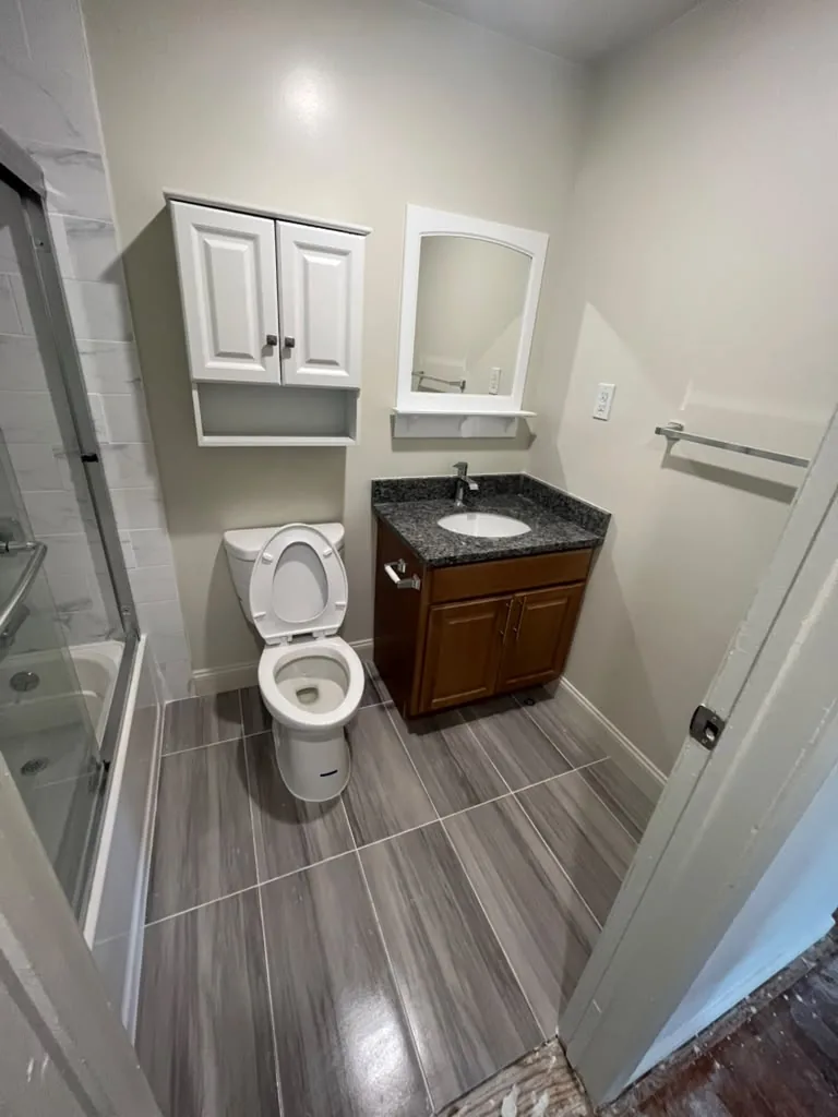 Glass shower enclosure beside a wood vanity