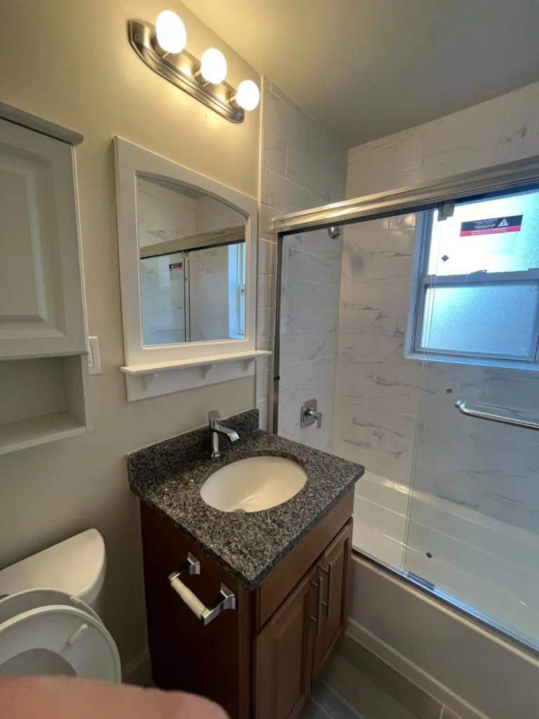 Glass shower enclosure with vanity and sconce lighting