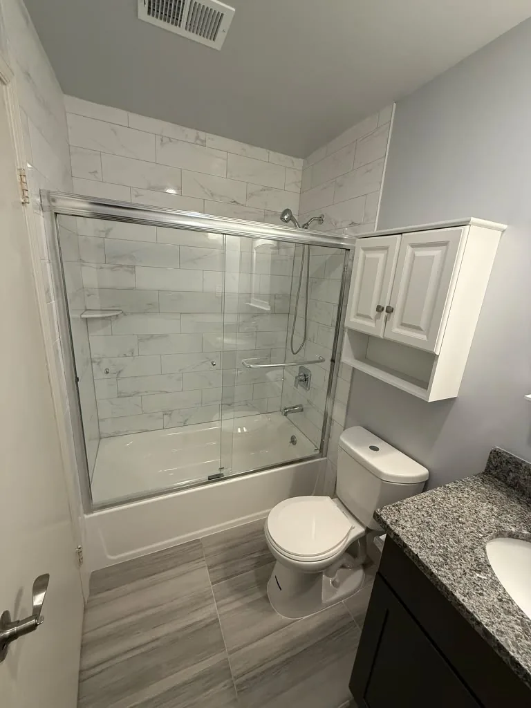 Glass shower enclosure in a white tiled bathroom