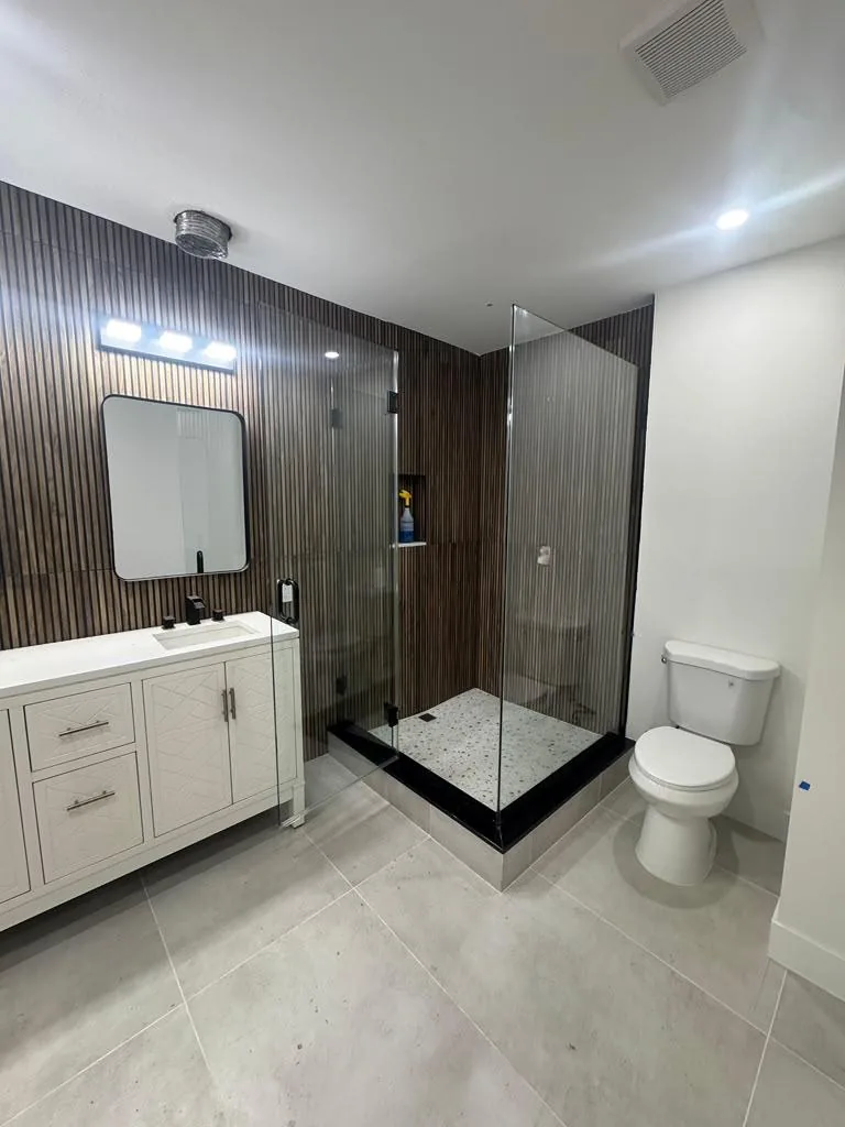 Glass shower enclosure with slatted wall and white vanity