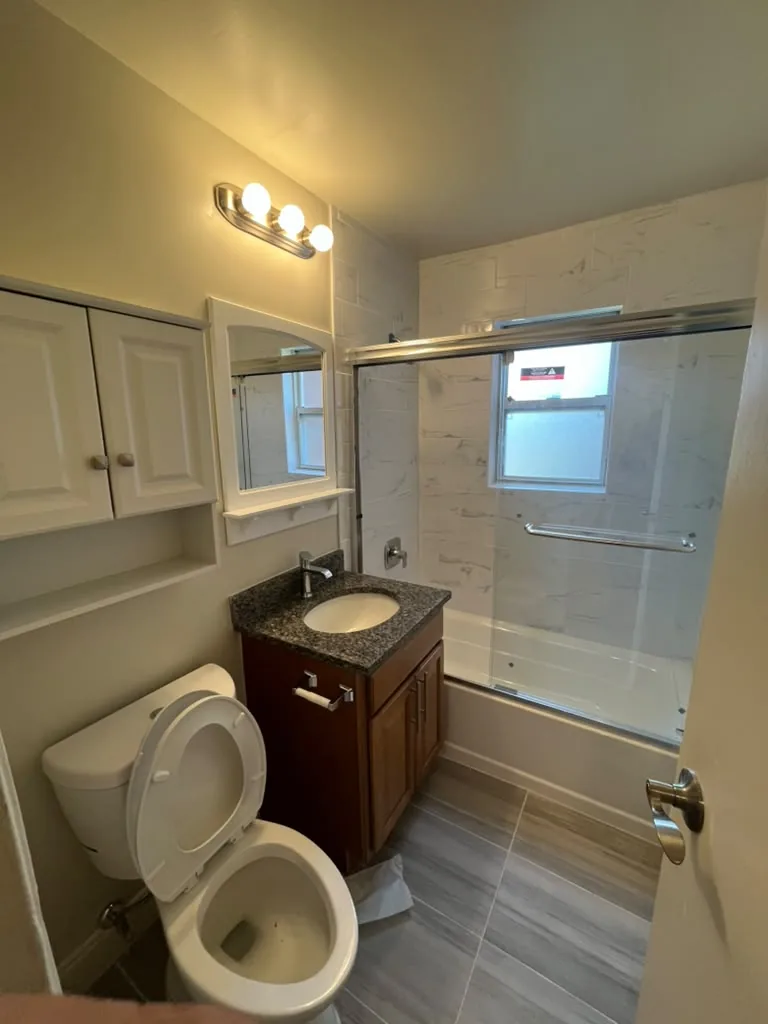 Glass tub enclosure with vanity and sconce lighting