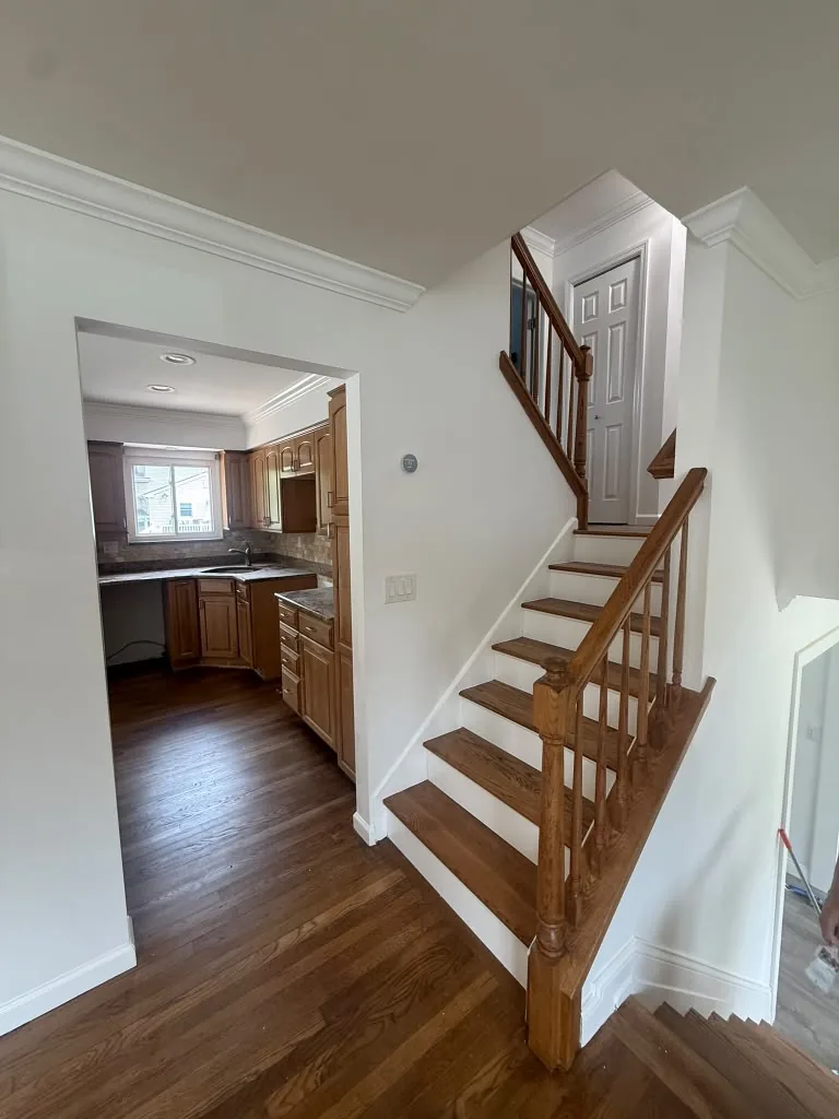 Staircase with wood handrail beside the kitchen