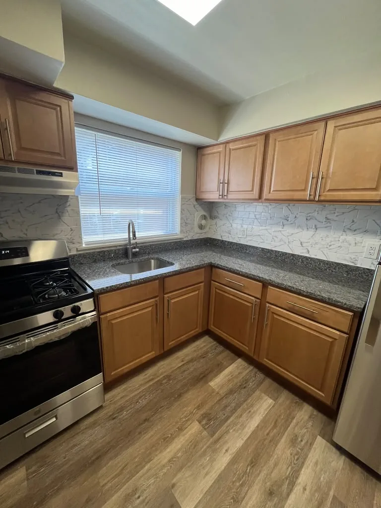 U shaped kitchen with wood cabinets and granite counters