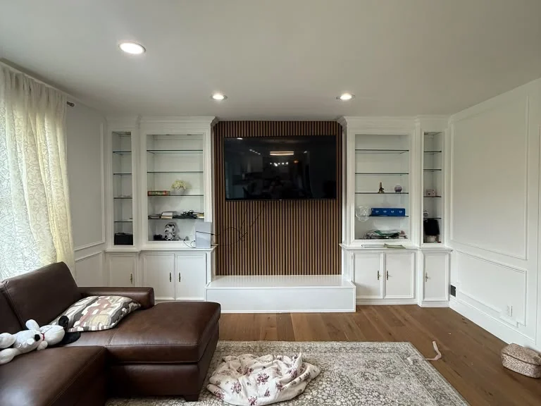 Living room finished with custom built-ins, slatted feature wall and mounted television