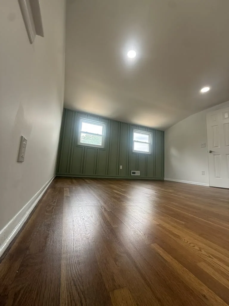 Room with deep green accent wall and refinished hardwood floors